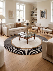 Au sol d'un salon élégant, un tapis rond en laine et viscose alterne ivoire, anneau marron et larges rayures noires