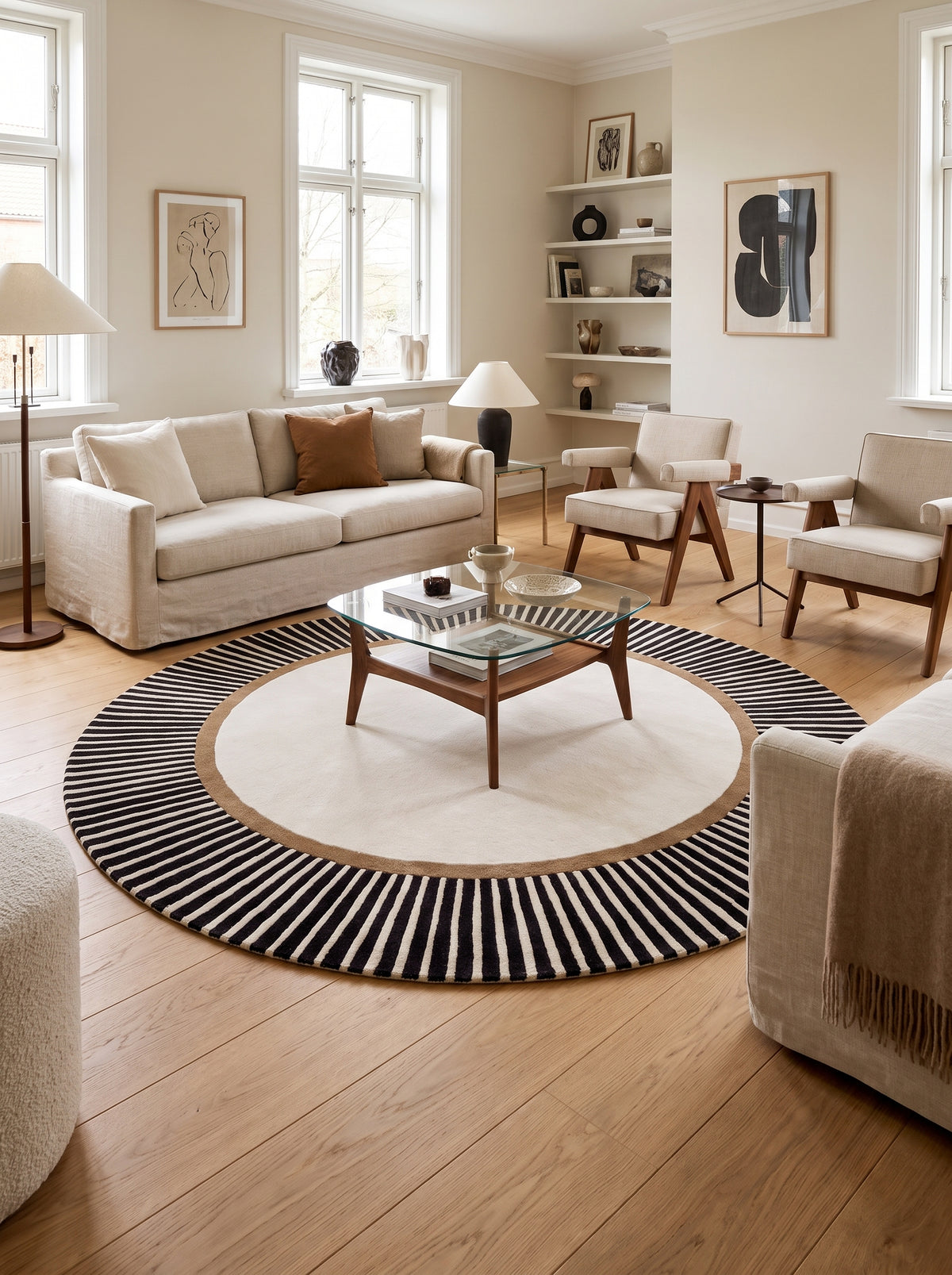 Au sol d'un salon élégant, un tapis rond en laine et viscose alterne ivoire, anneau marron et larges rayures noires