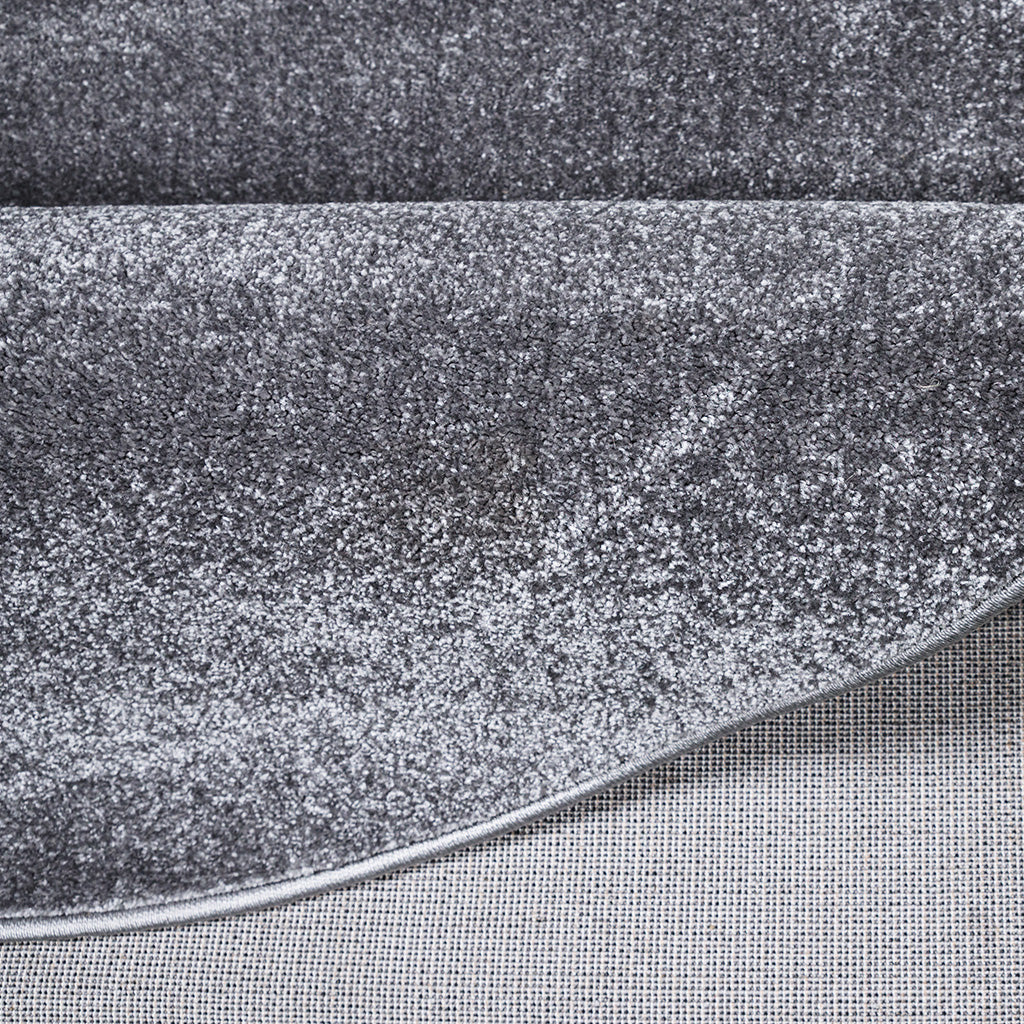 Tapis moelleux à poils longs dans des nuances de gris clair et anthracite, avec le revers du tapis visible