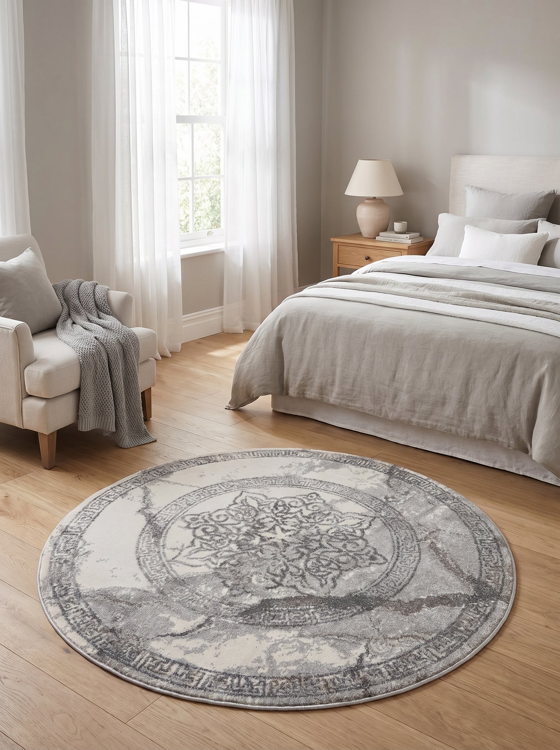 Tapis rond crème et gris, à motif médaillon central orné et contour géométrique, sur parquet clair dans une chambre