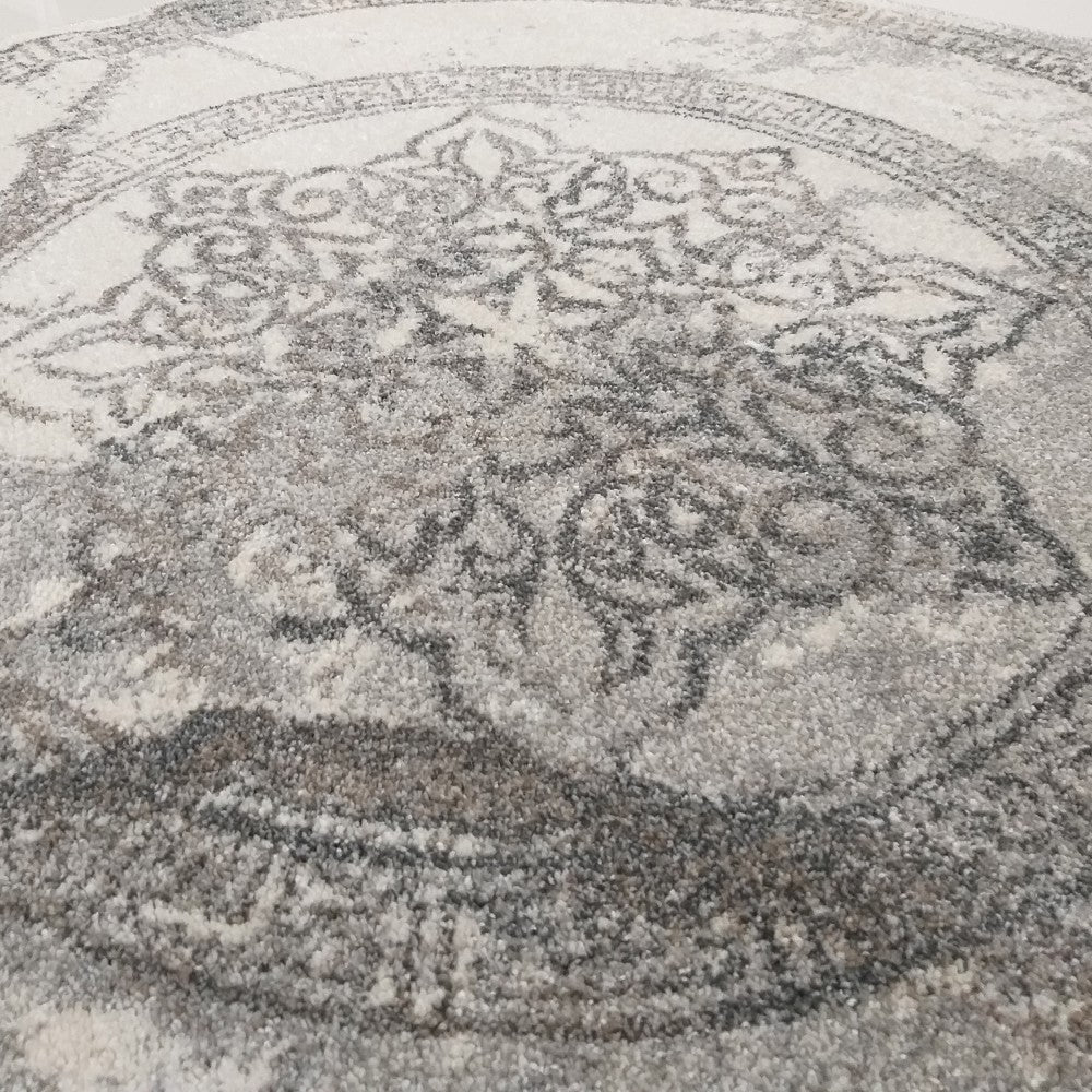 Tapis aux poils doux avec un motif médaillon central et une bordure en gris foncé sur fond blanc et gris clair