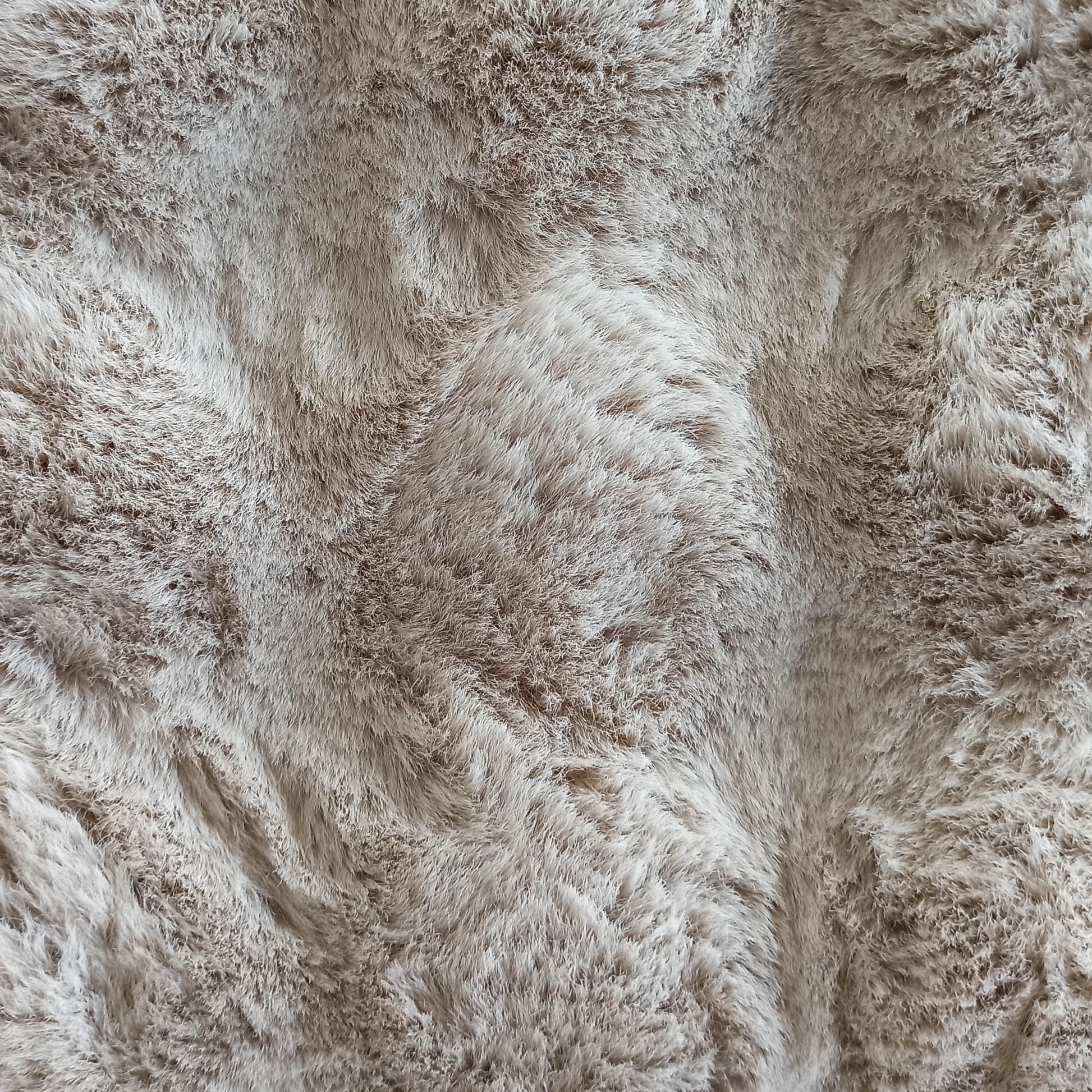 Tapis texturé à poils longs et doux, de couleur beige clair nuancé avec des touches plus foncées