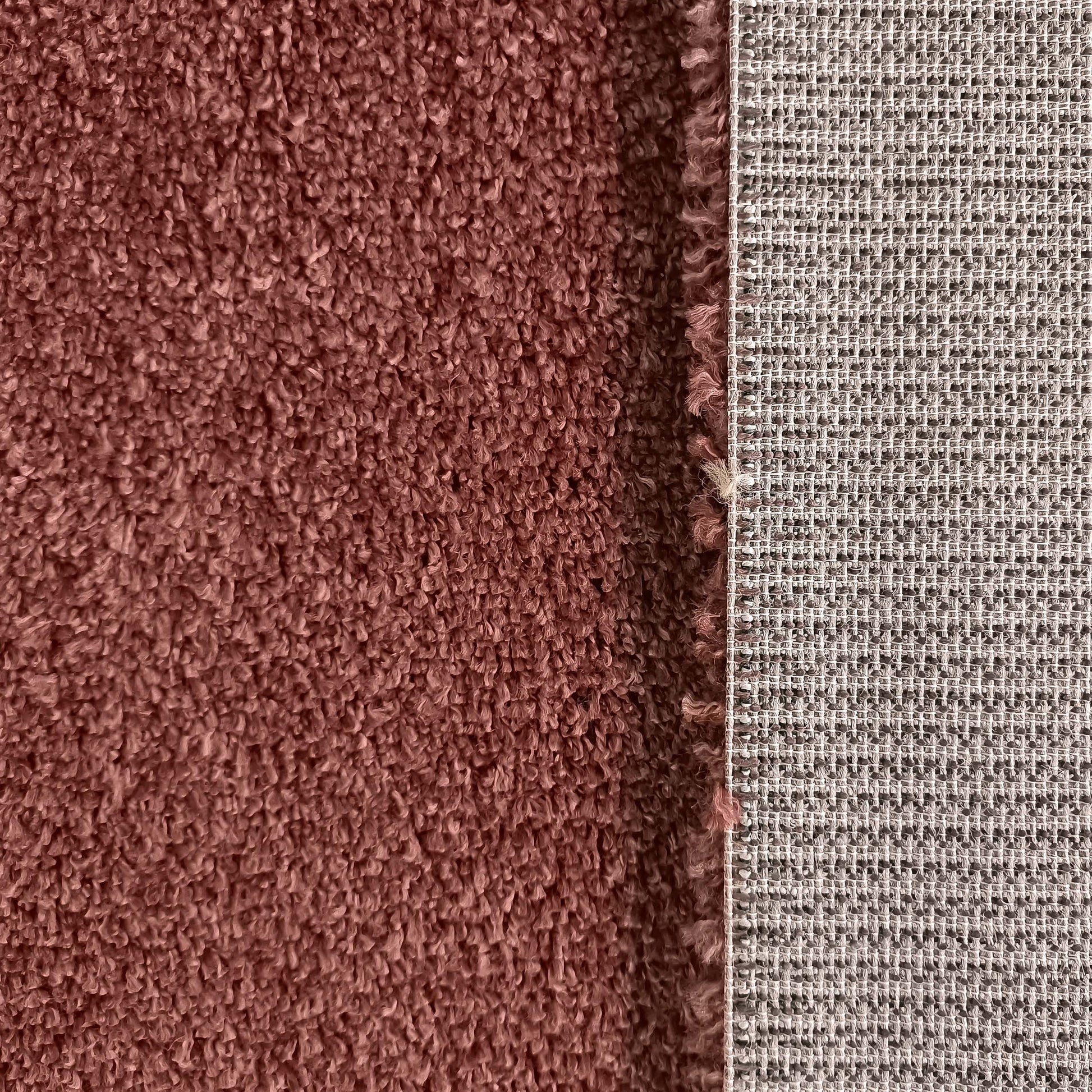 Surface d'un tapis brun-rose à boucles texturées, et son dossier tissé à motif de grille beige et gris