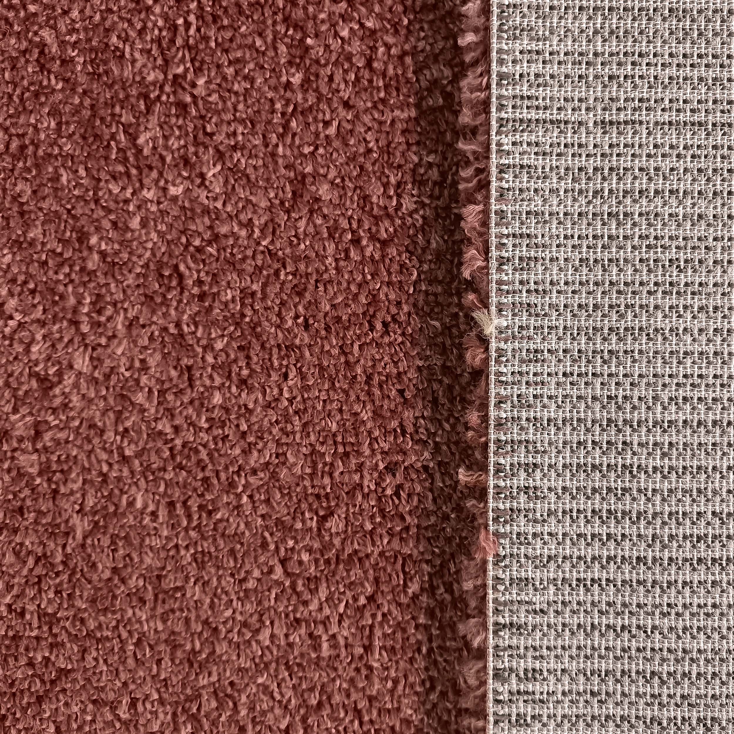 Surface d'un tapis brun-rose à boucles texturées, et son dossier tissé à motif de grille beige et gris