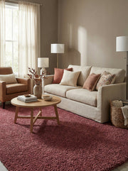 Grand tapis rectangulaire à poils longs rouge bordeaux dans un salon lumineux avec canapé beige et fauteuil en cuir