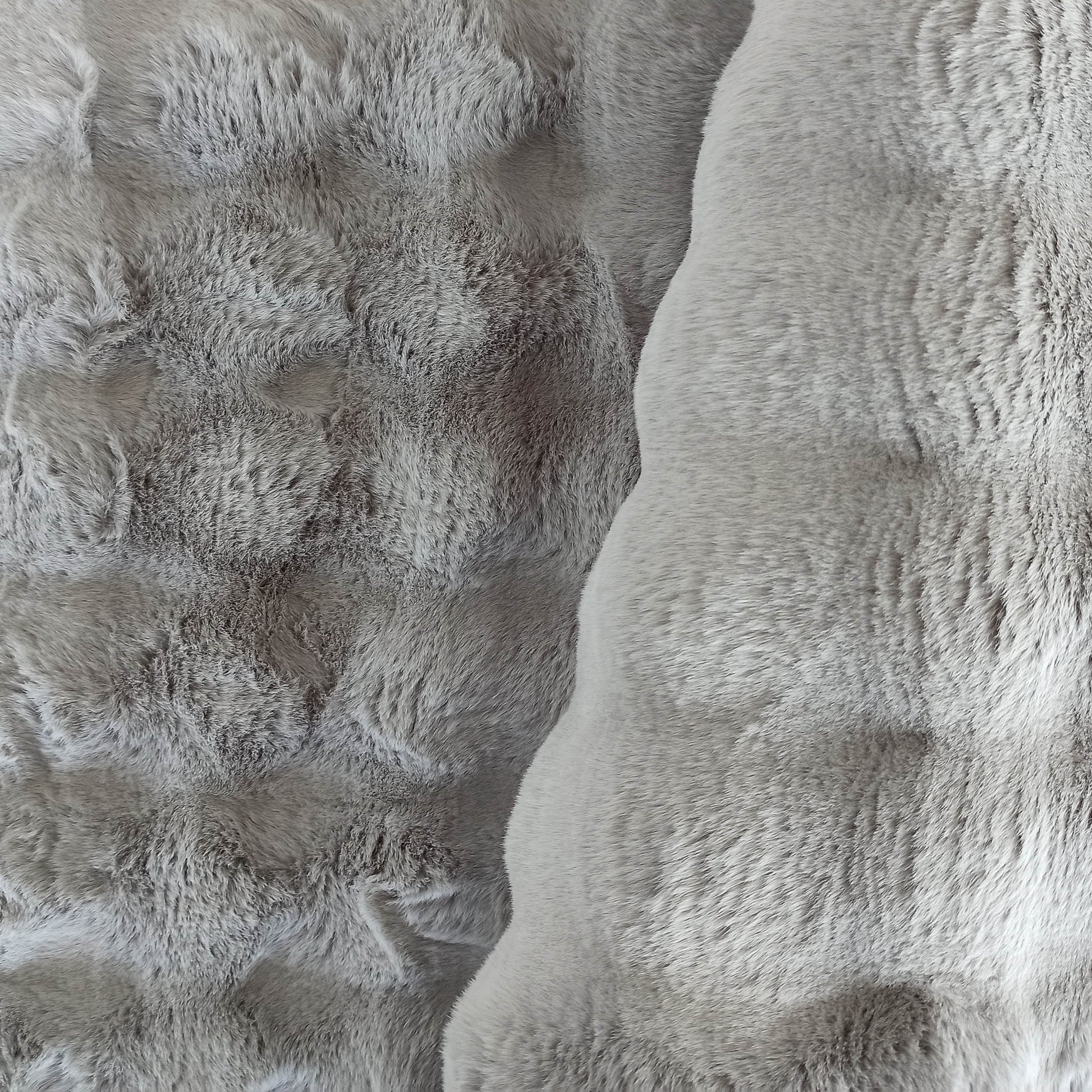 Tapis épais et doux en nuances de gris clair, avec une texture rappelant la fourrure ou la laine shaggy