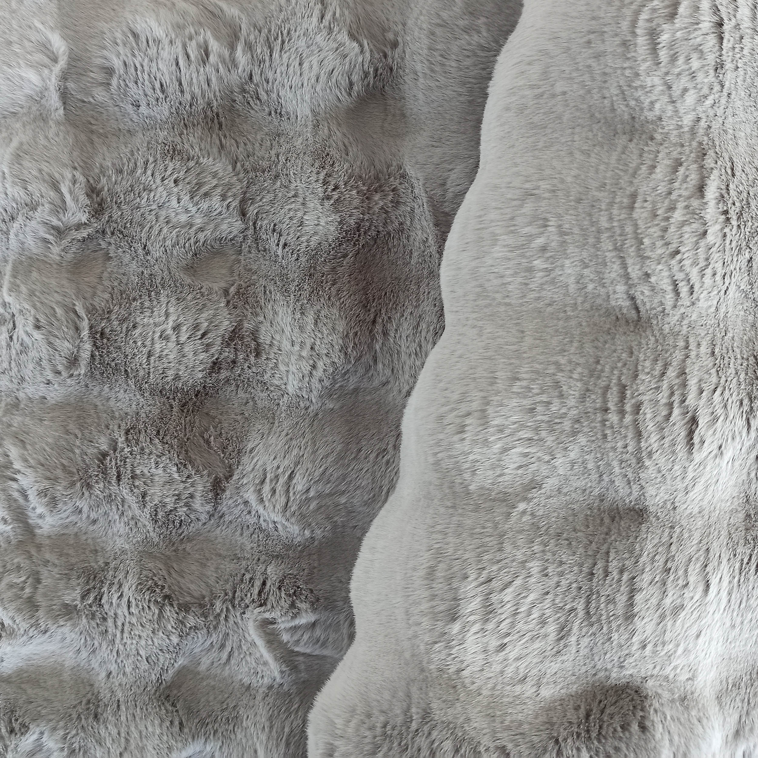 Tapis épais et doux en nuances de gris clair, avec une texture rappelant la fourrure ou la laine shaggy
