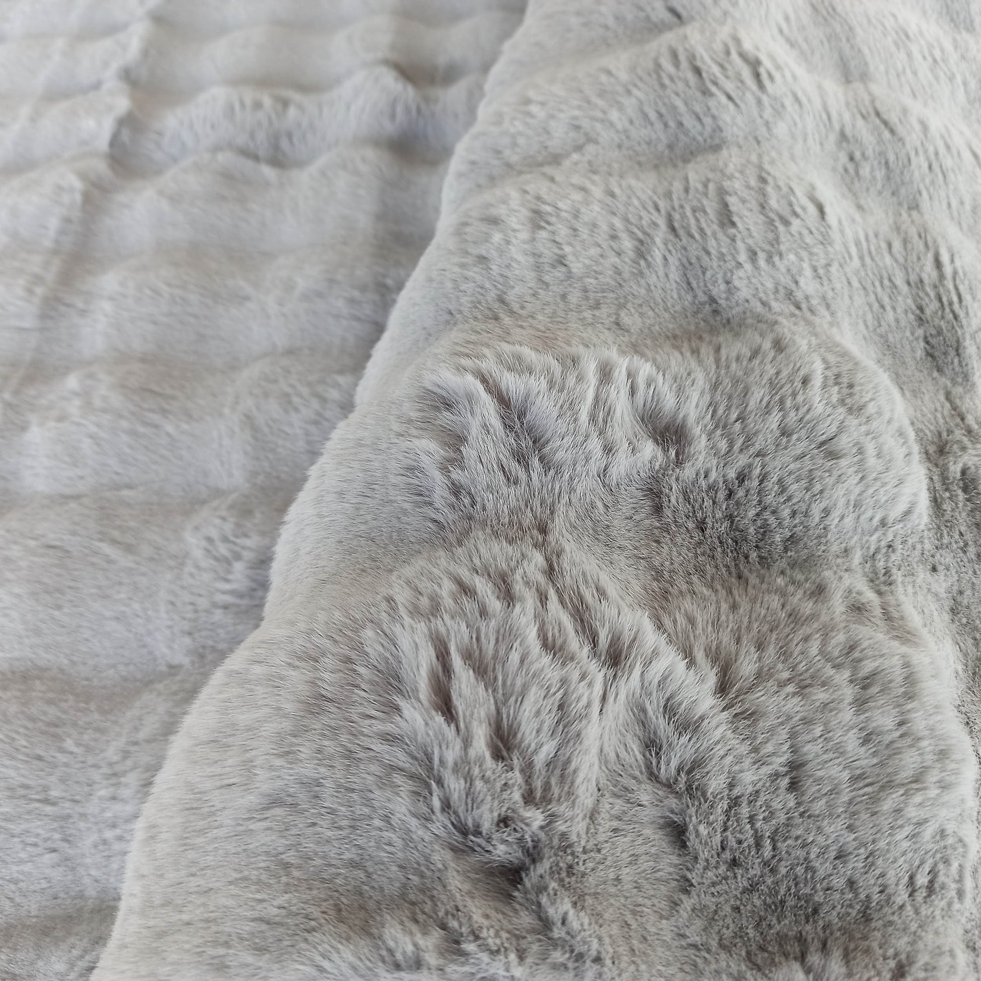 Gros plan sur un tapis gris à poils longs, dont la texture douce évoque de la fausse fourrure
