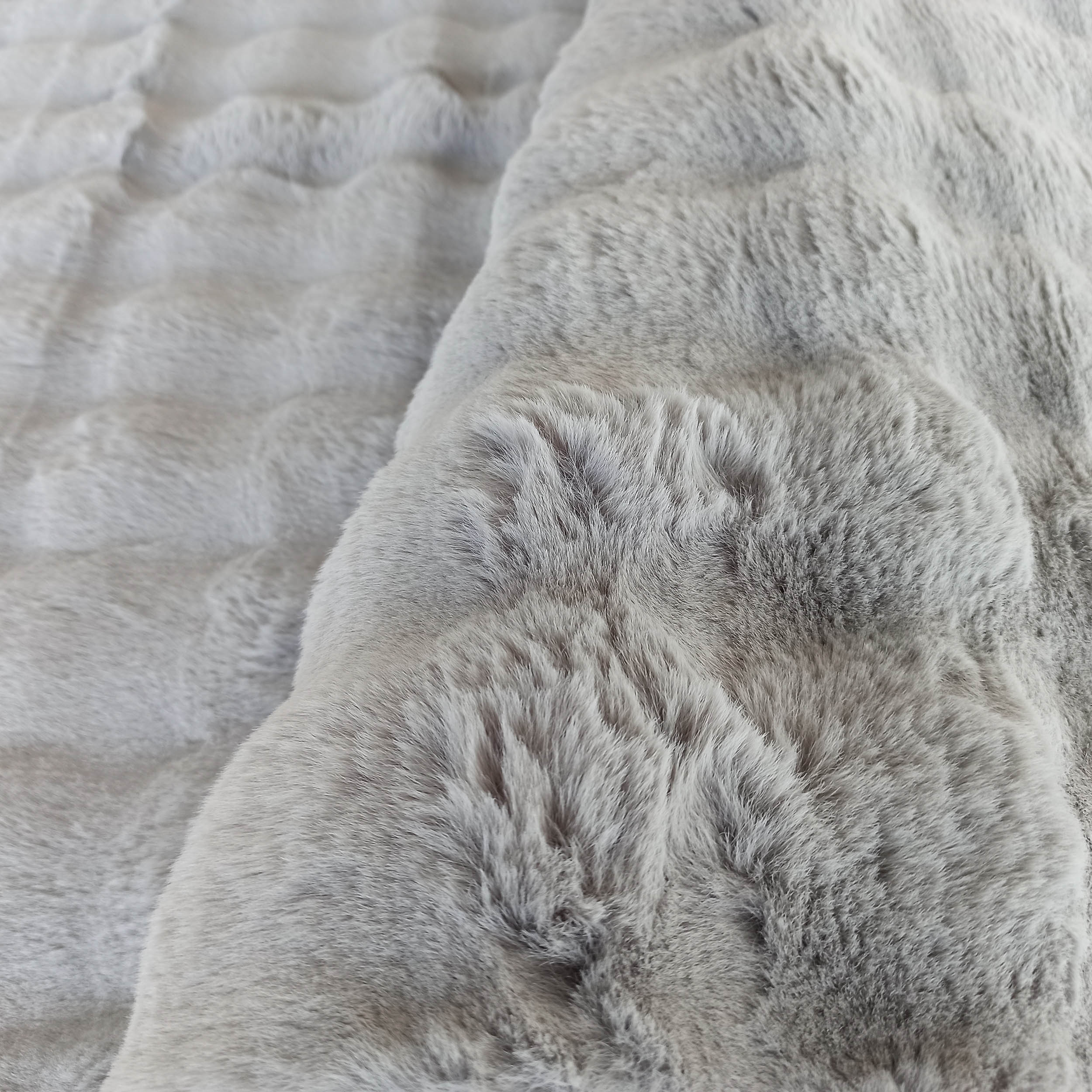 Gros plan sur un tapis gris à poils longs, dont la texture douce évoque de la fausse fourrure