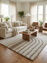 Tapis rectangulaire à poils longs crème avec des rayures marron en arc de cercle, posé sur un parquet dans un salon lumineux