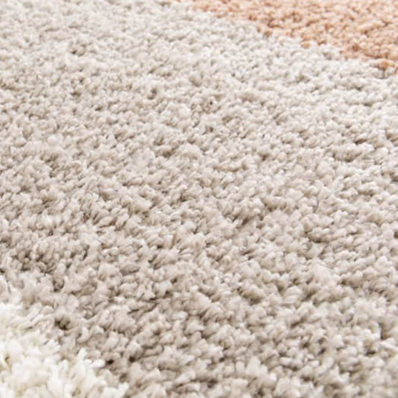 Gros plan sur un tapis shaggy doux et moelleux avec des bandes de couleurs blanc cassé, beige clair et marron pêche