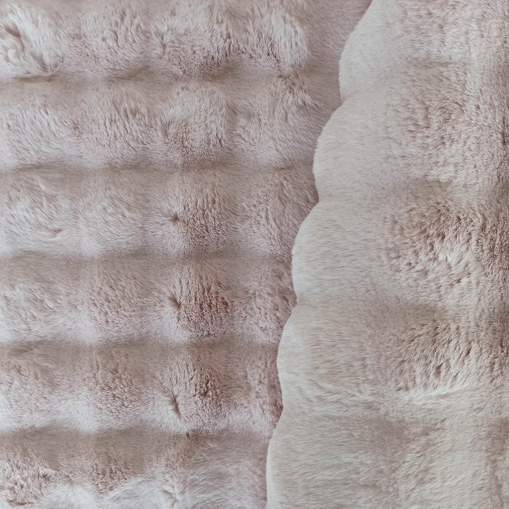 Tapis rose poudré doux à l'aspect fourrure. Sa surface présente des ondulations texturées à gauche et une zone plus lisse à droite