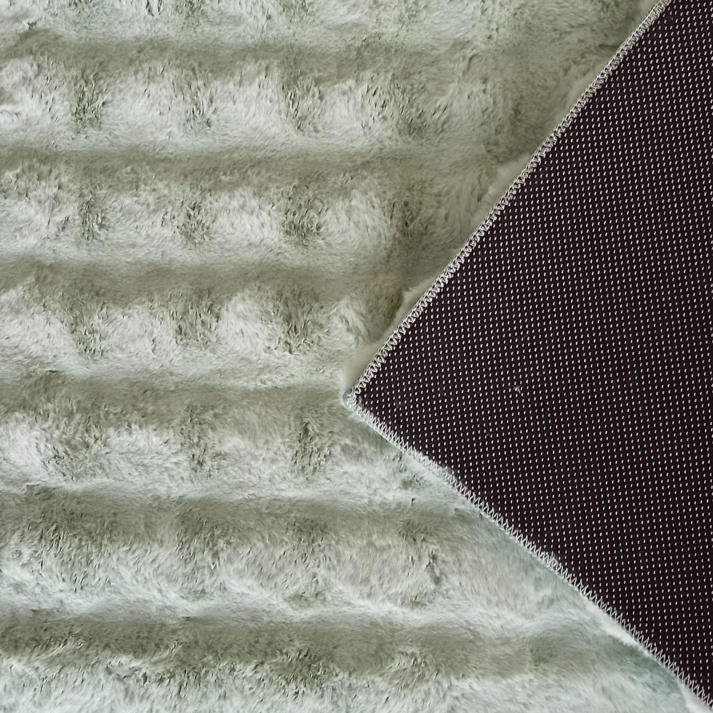 Tapis doux à poils longs vert menthe avec un motif en côtes et un revers antidérapant noir à petits points blancs visible