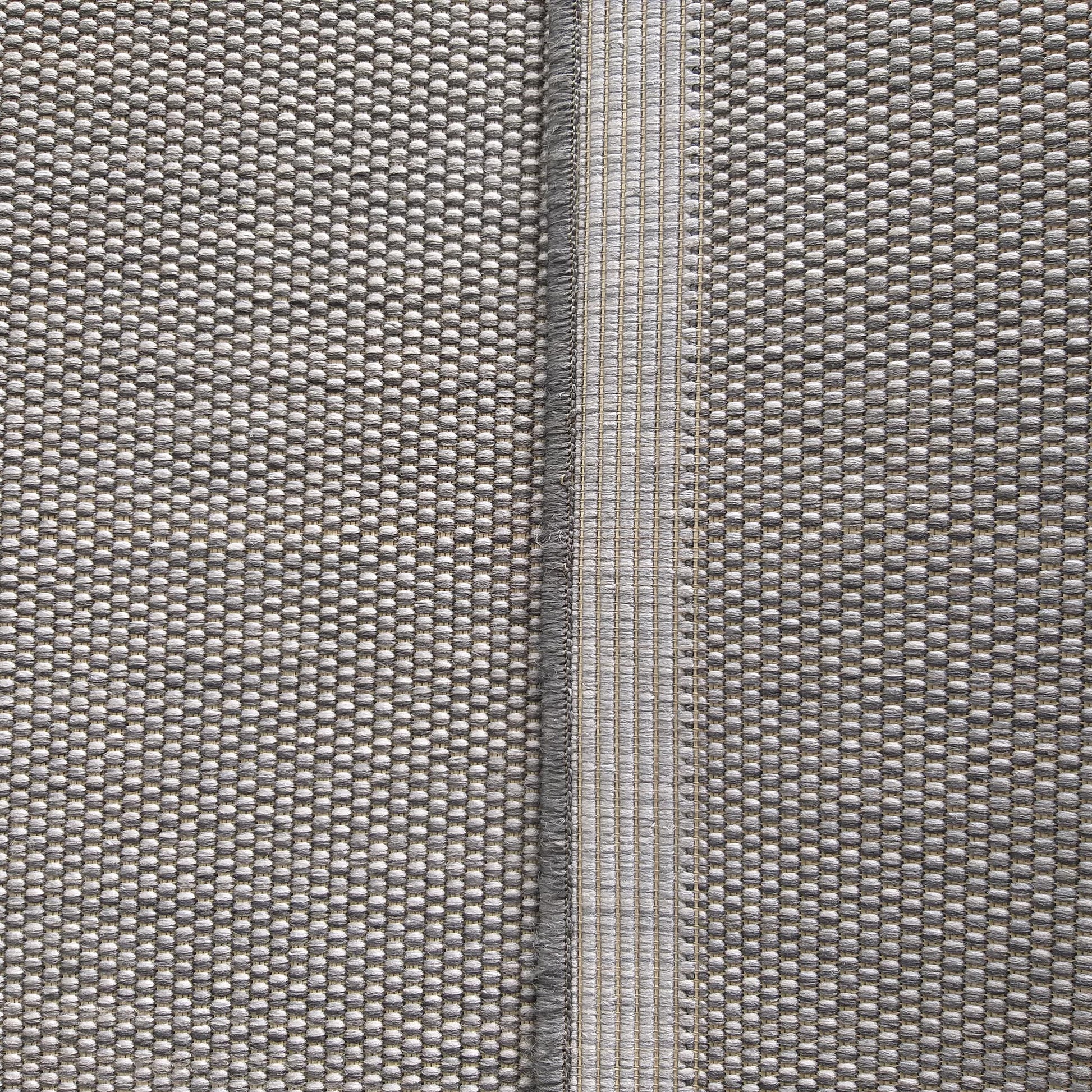 Tapis tissé gris présentant une texture bouclée et une bande centrale verticale au tissage plus plat