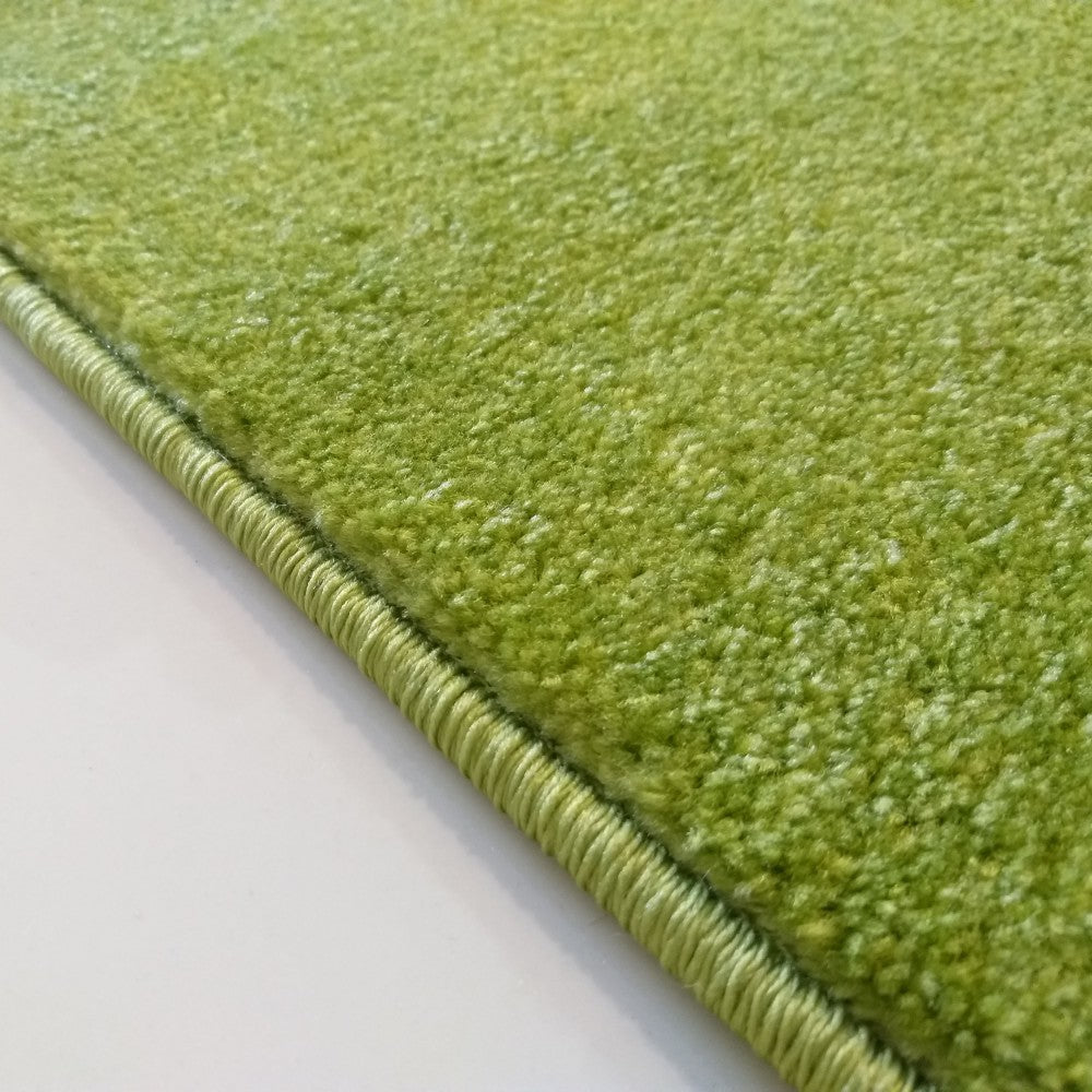 Gros plan d'un tapis vert vibrant et chiné, à la texture moelleuse, avec une finition de bordure cousue