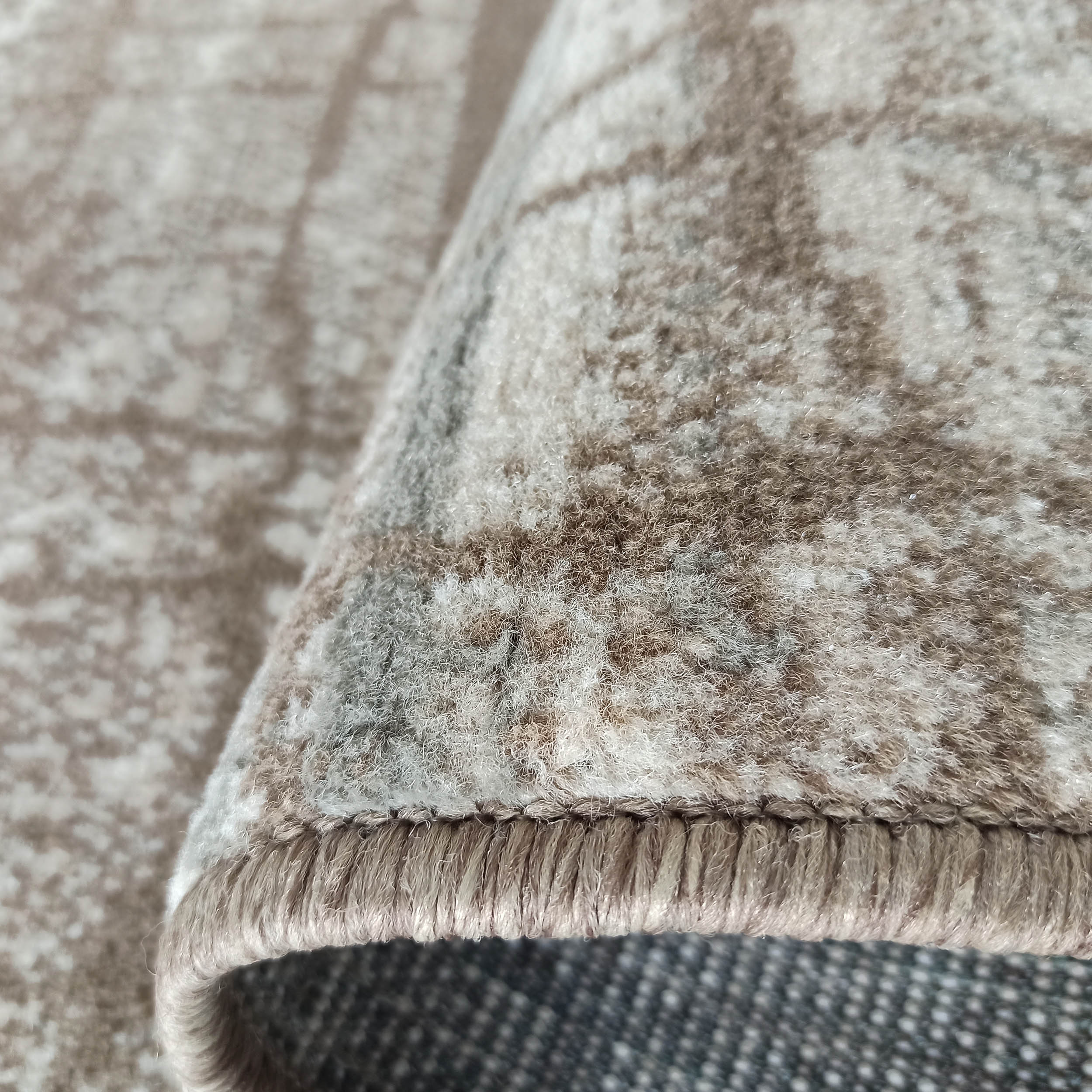 Tapis beige et marron aux motifs abstraits, avec une texture douce et moelleuse de longs poils, montrant son bord ourlé