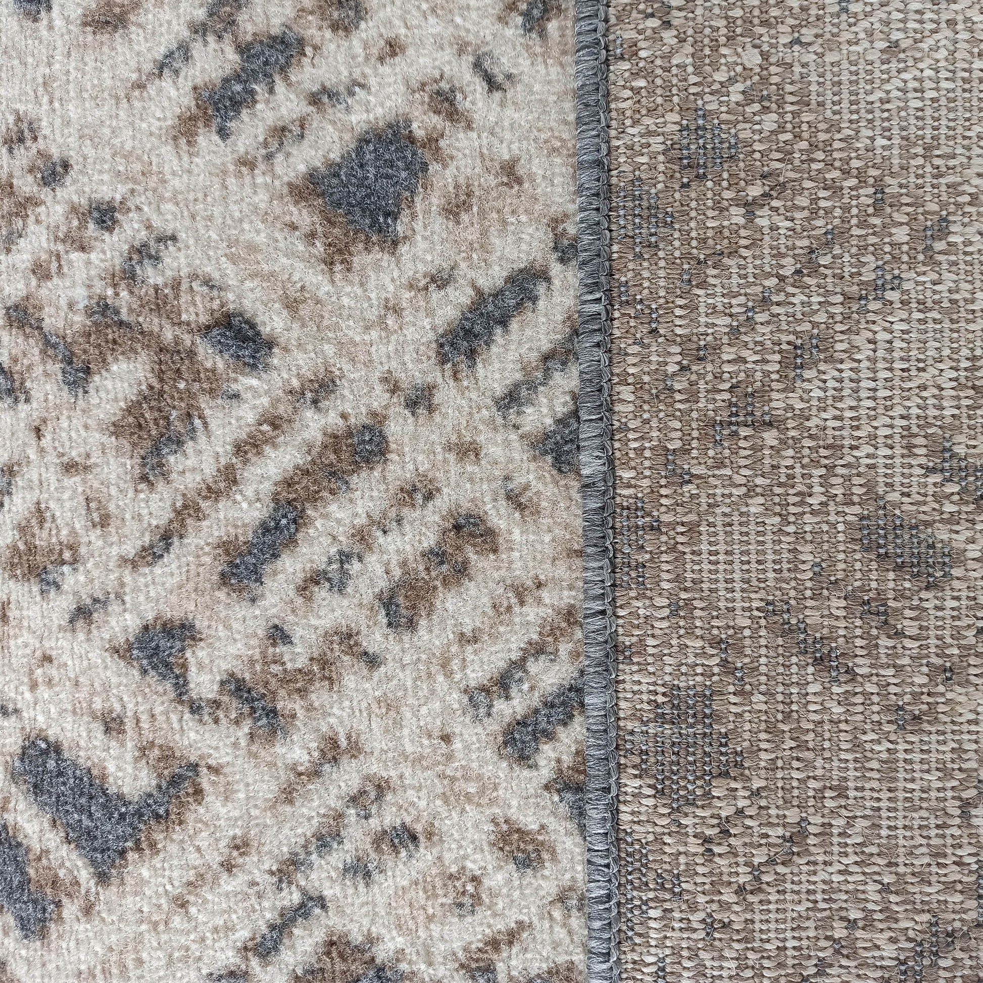 Tapis à surface douce avec motifs abstraits beige, marron et gris, et envers tissé marron séparés par une couture grise