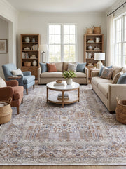 Tapis rectangulaire aux motifs floraux et géométriques délavés en beige, bleu lavande et rouille dans un salon