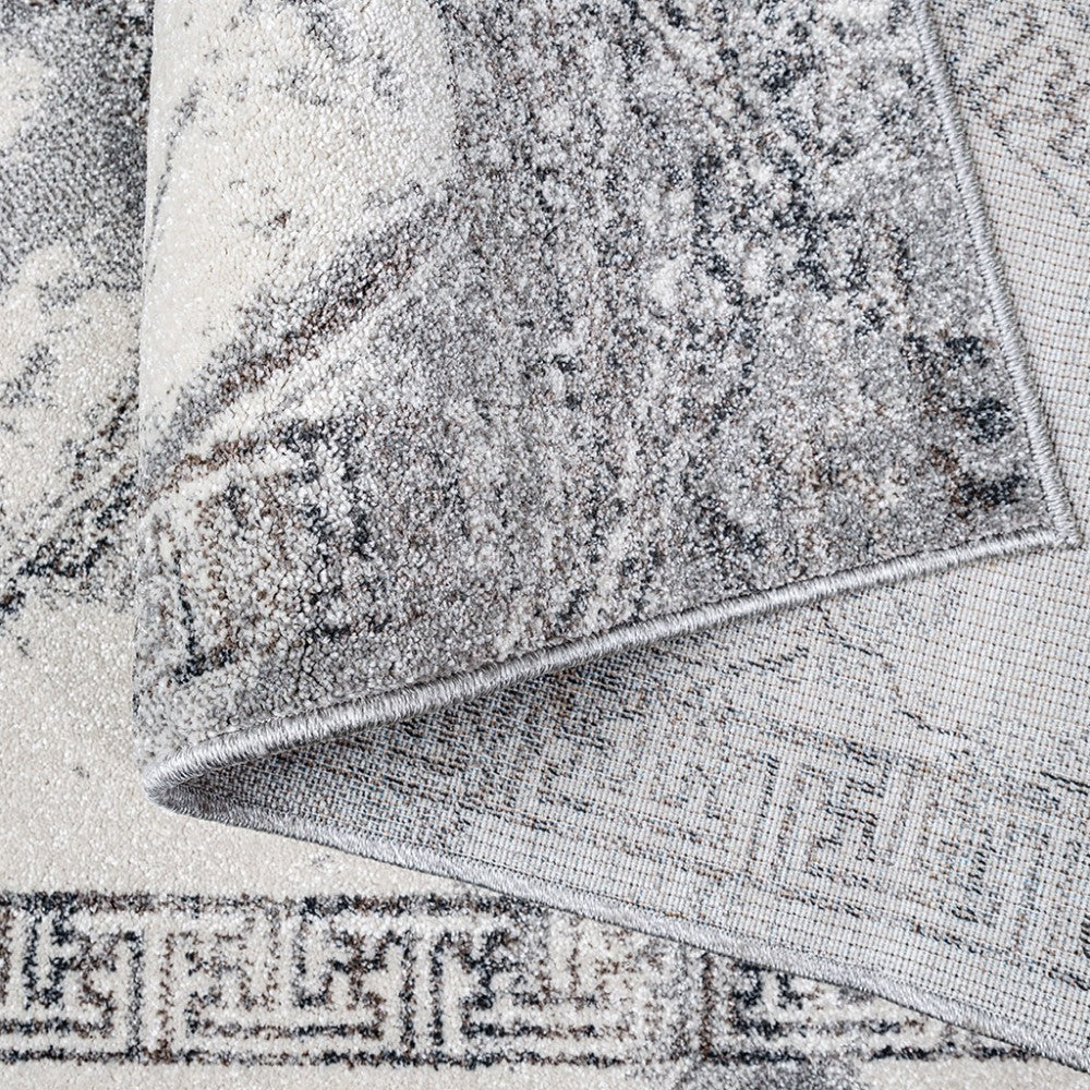 Tapis à texture douce, tons gris, crème et beige, avec motifs abstraits et bordure à grecque sur le pli