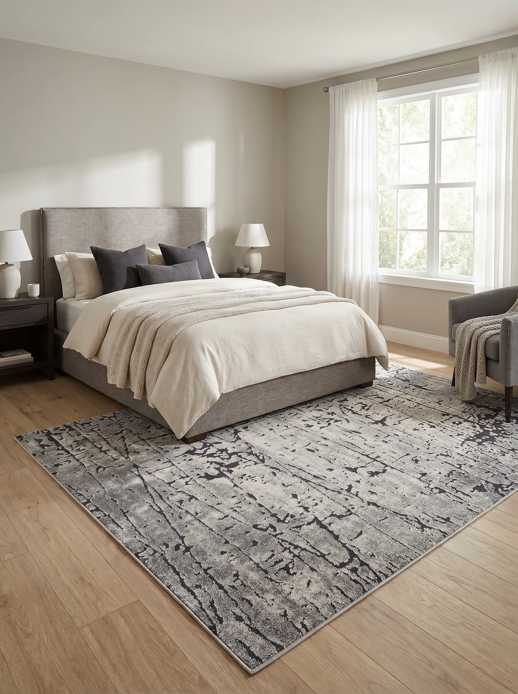 Grand tapis rectangulaire gris clair à motifs abstraits foncés, texture douce, sur parquet en bois d'une chambre moderne