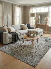 Tapis rectangulaire aux motifs abstraits gris clair et anthracite, posé sur un parquet clair dans un salon moderne