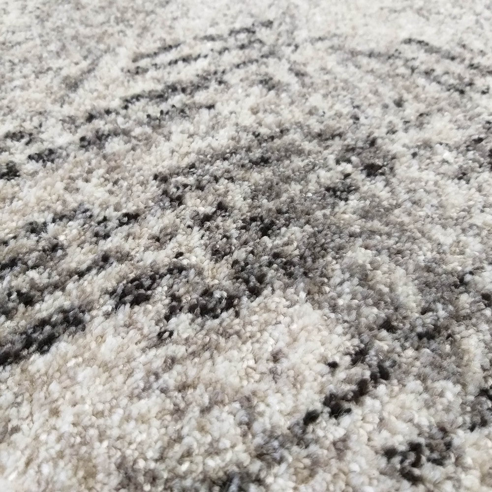 Tapis doux à poils longs, mêlant des tons de blanc, gris clair et noir pour un motif abstrait moucheté et texturé