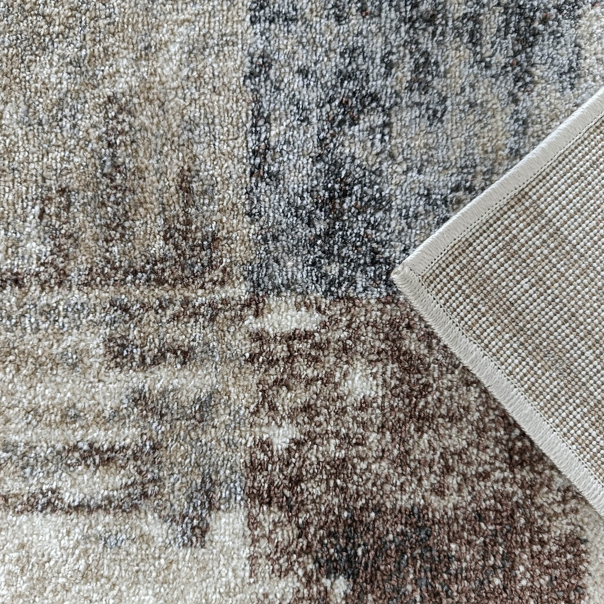 Tapis texturé aux motifs abstraits beiges, gris et bruns, avec son revers tissé beige clair à petits points et bordure cousue
