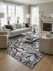 Tapis rectangulaire gris et noir aux motifs floraux et volutes, texture douce, dans un salon lumineux