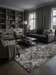 Tapis rectangulaire aux motifs floraux ornementaux noirs, gris et blanc cassé, avec un aspect vieilli, dans un salon moderne