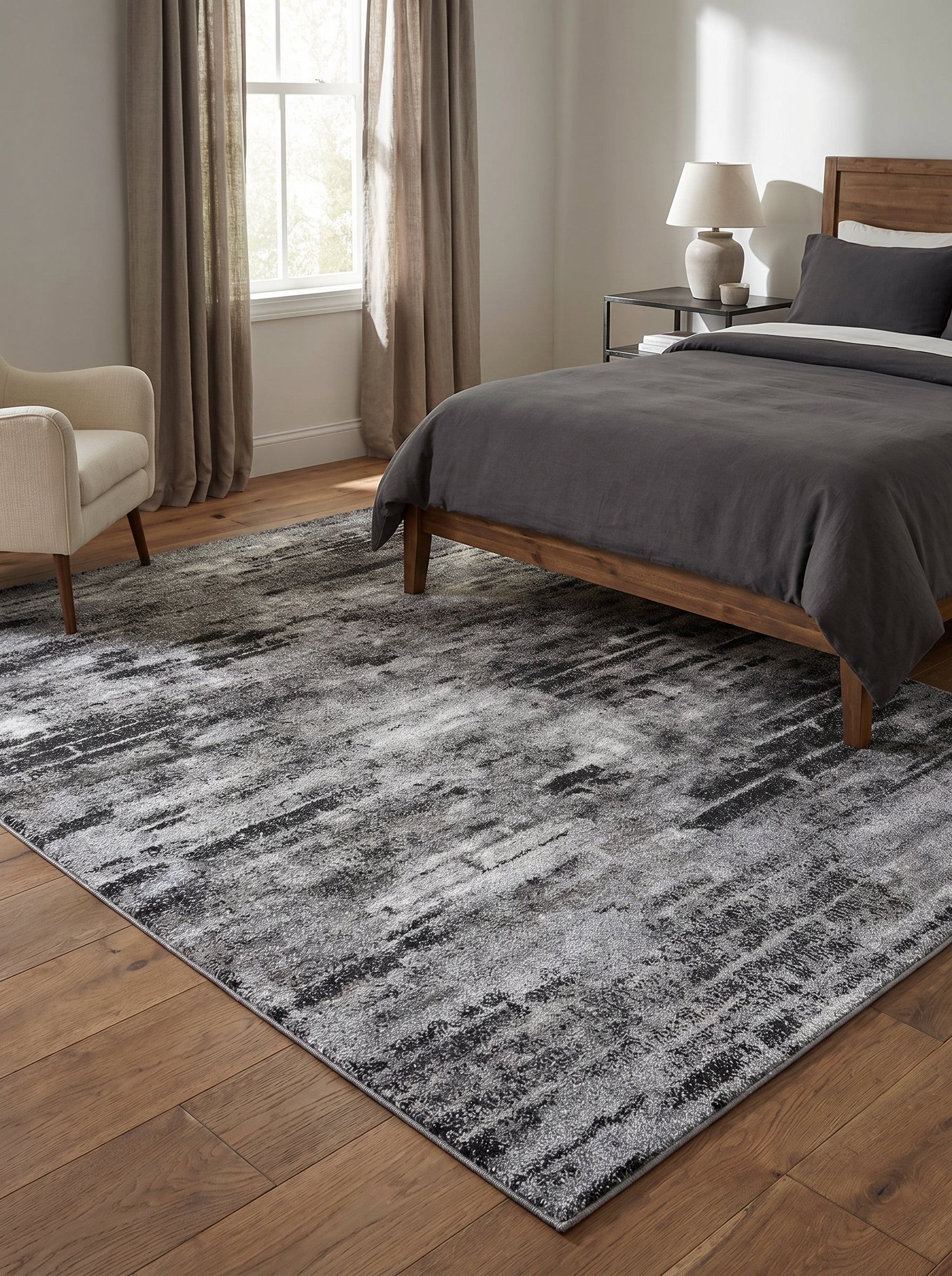 Tapis rectangulaire aux motifs abstraits et brossés en nuances de gris clair et foncé, posé sur parquet dans une chambre moderne