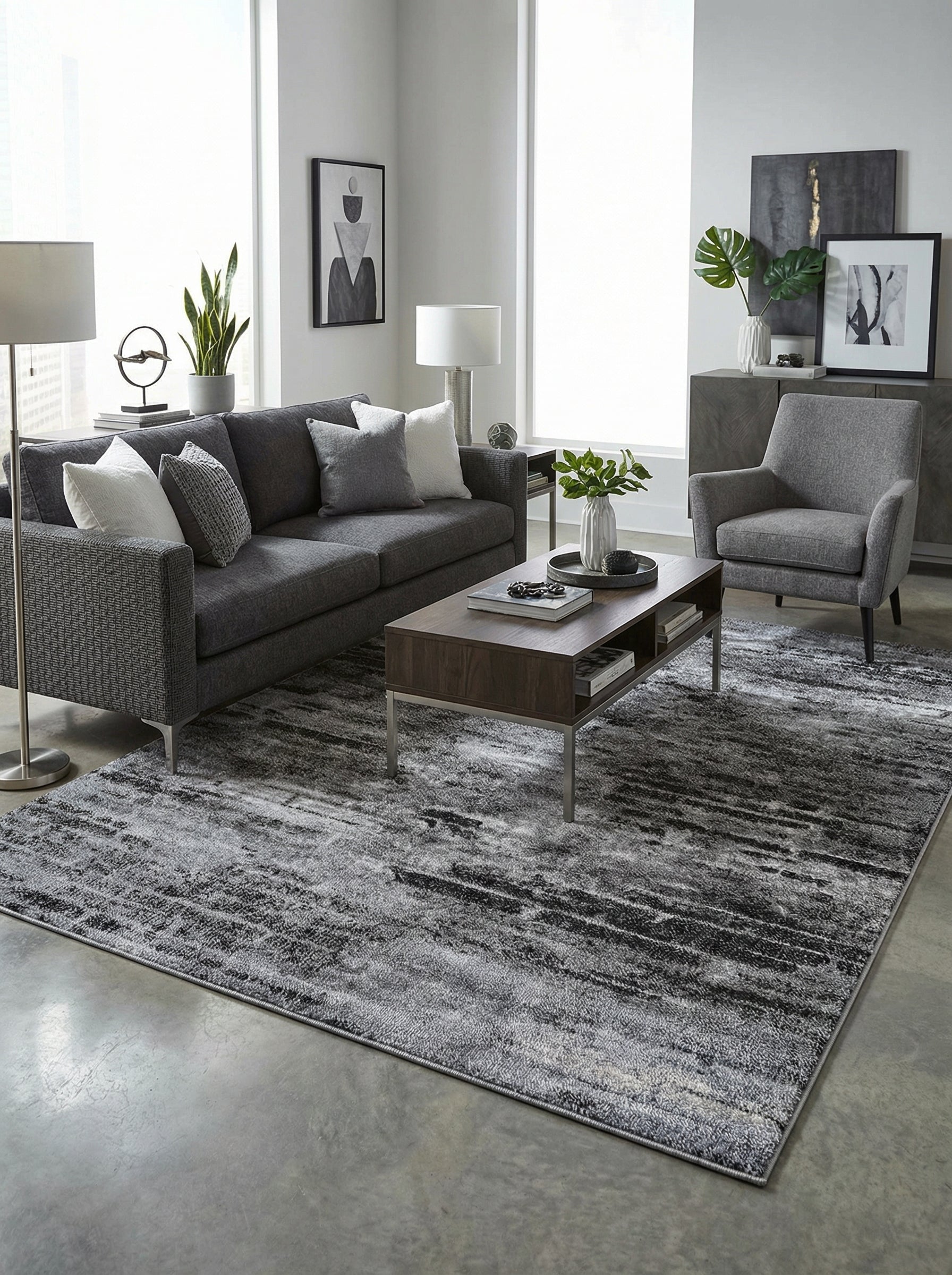 Tapis rectangulaire aux teintes de gris, noir et blanc avec un motif abstrait strié. Il est visible dans un salon moderne
