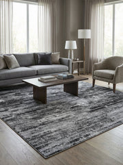 Grand tapis rectangulaire texturé aux nuances de gris clair, gris foncé et noir, avec un motif abstrait strié, dans un salon