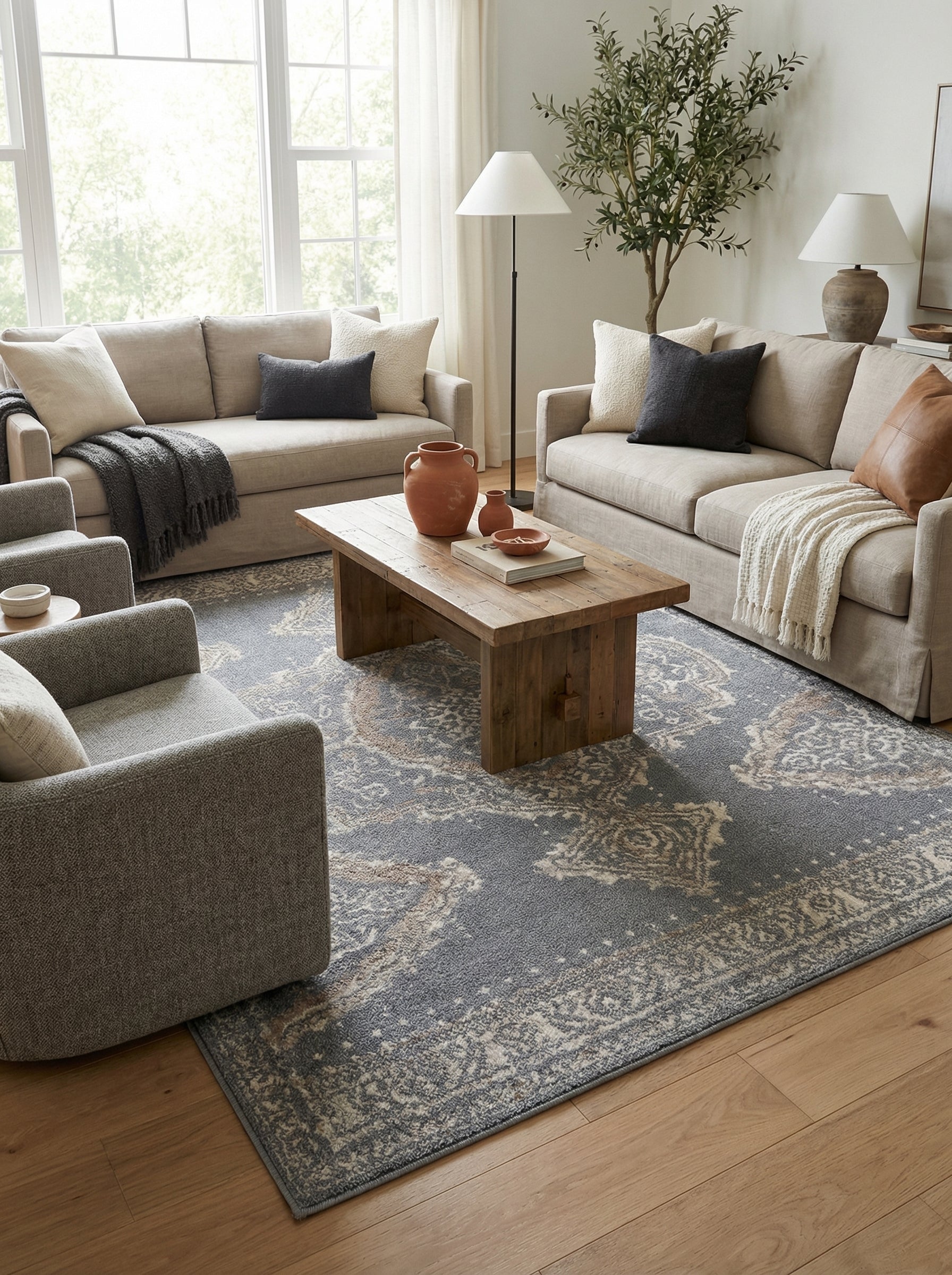 Tapis rectangulaire bleu-gris à motifs médaillon traditionnels crème et marron, à l'aspect vieilli, sur un parquet clair dans un salon