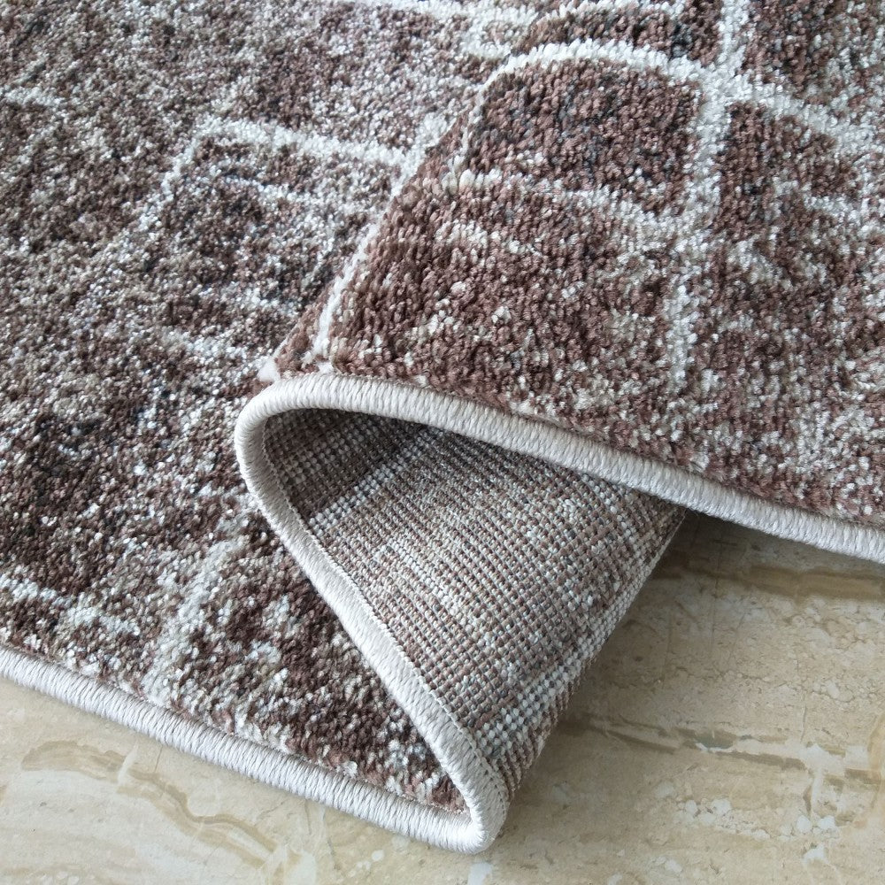 Tapis à poils marron moucheté et crème avec motifs abstraits, son envers tissé beige et ses bords roulés sur carrelage