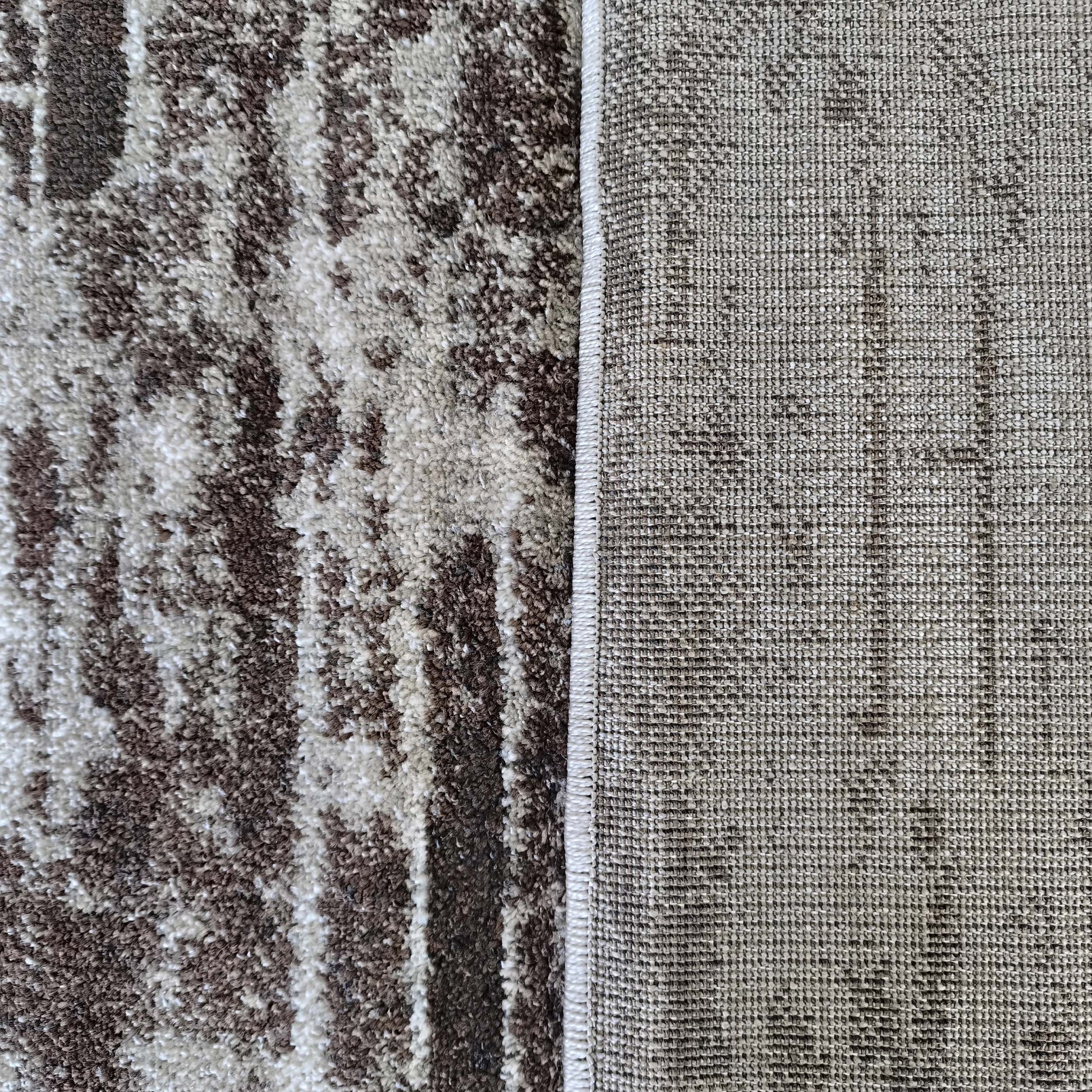 Tapis montrant sa surface en poils longs marron et crème aux motifs abstraits et son envers tissé serré gris-beige