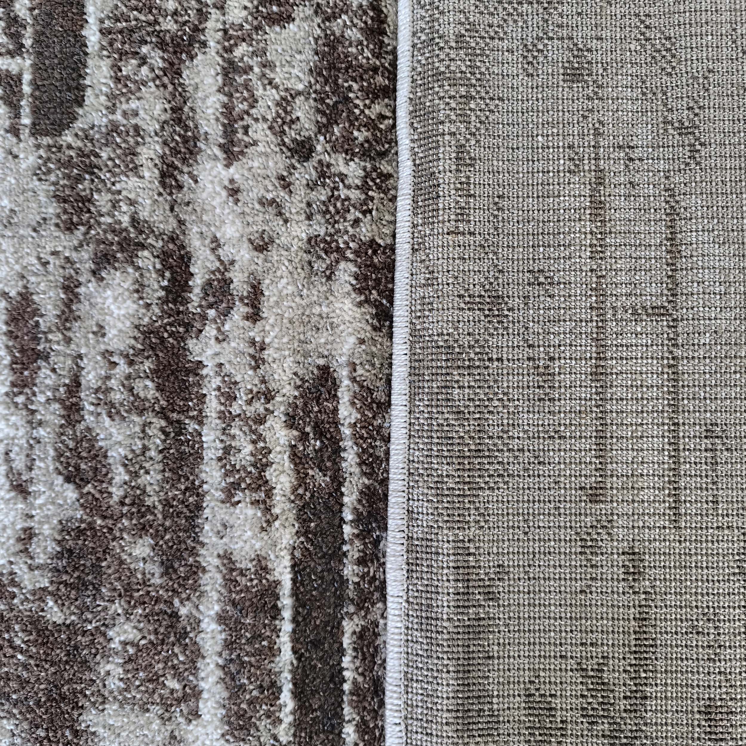 Tapis montrant sa surface en poils longs marron et crème aux motifs abstraits et son envers tissé serré gris-beige