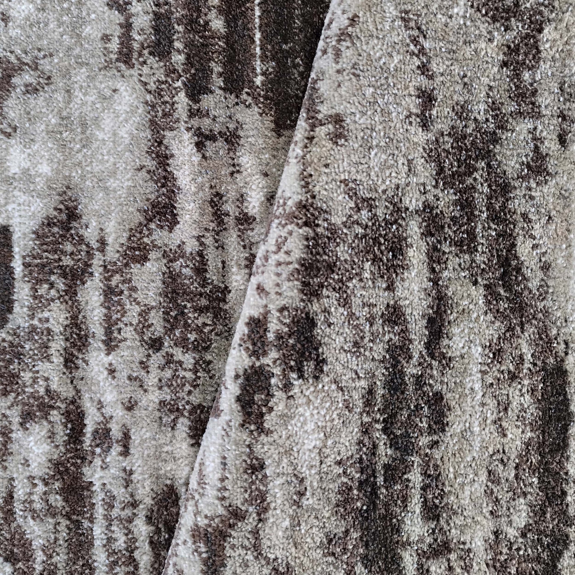 Tapis moelleux aux motifs abstraits marron foncé et beige clair, avec une texture rappelant l'écorce