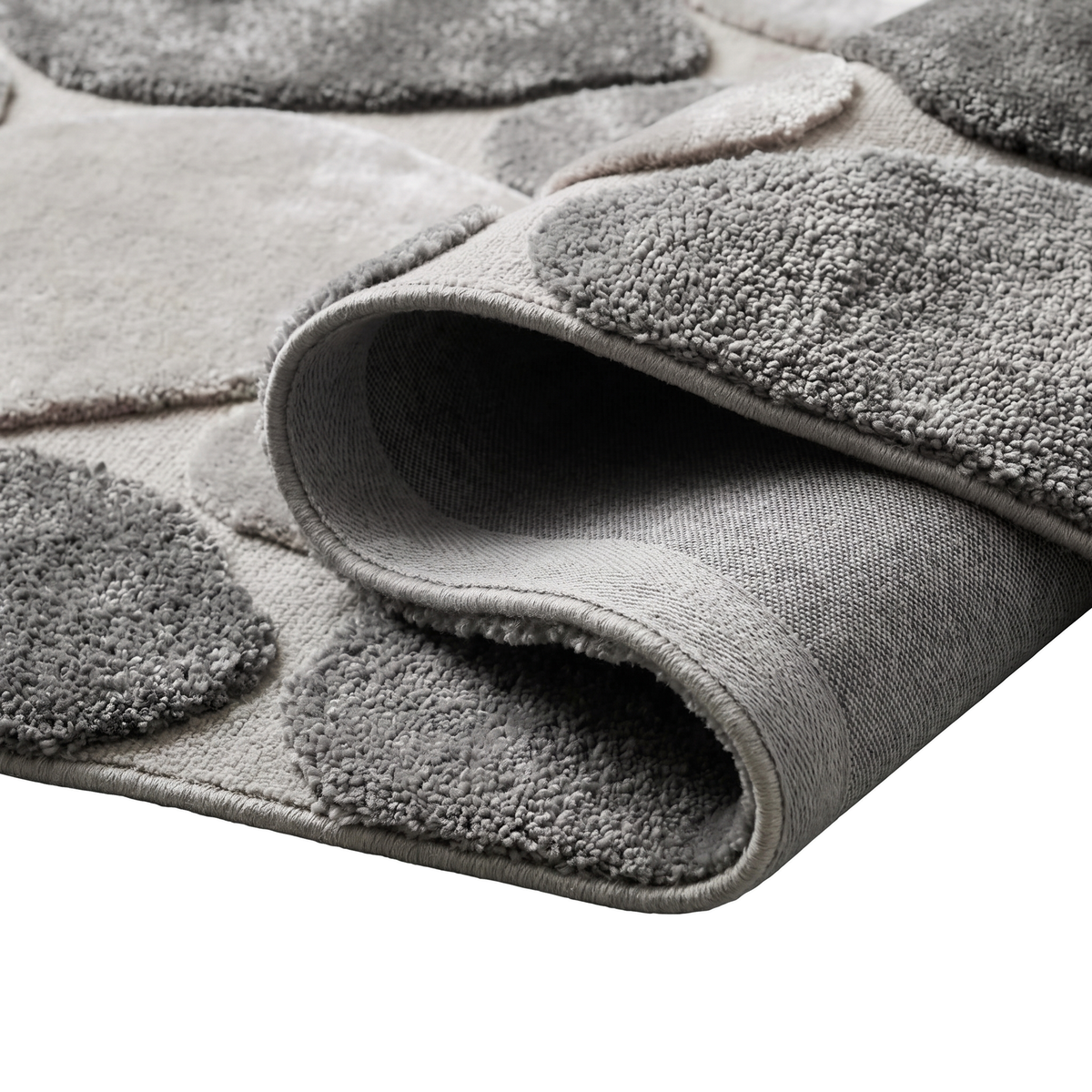 Le dos, l'épaisseur et les motifs de galets gris et taupe d'un tapis roulé en laine et viscose se dévoilent