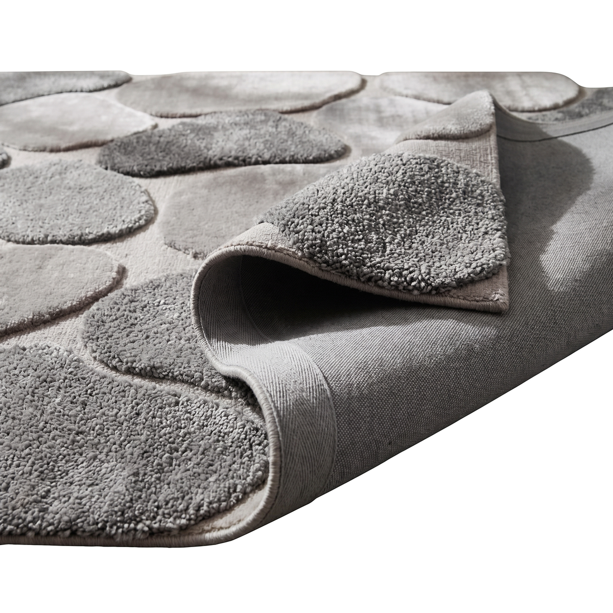 Un coin replié expose le dos tissé et le relief contrasté des galets gris et taupe en laine et viscose